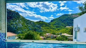 Una piscina con vistas a un paisaje montañoso y edificios al fondo.