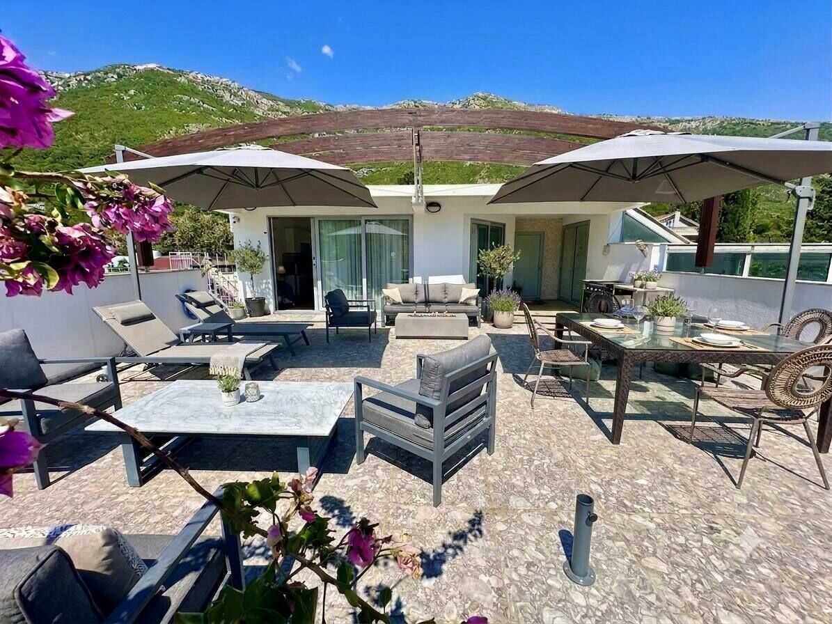 An outdoor patio with seating, umbrellas, and a view of a mountainous landscape.