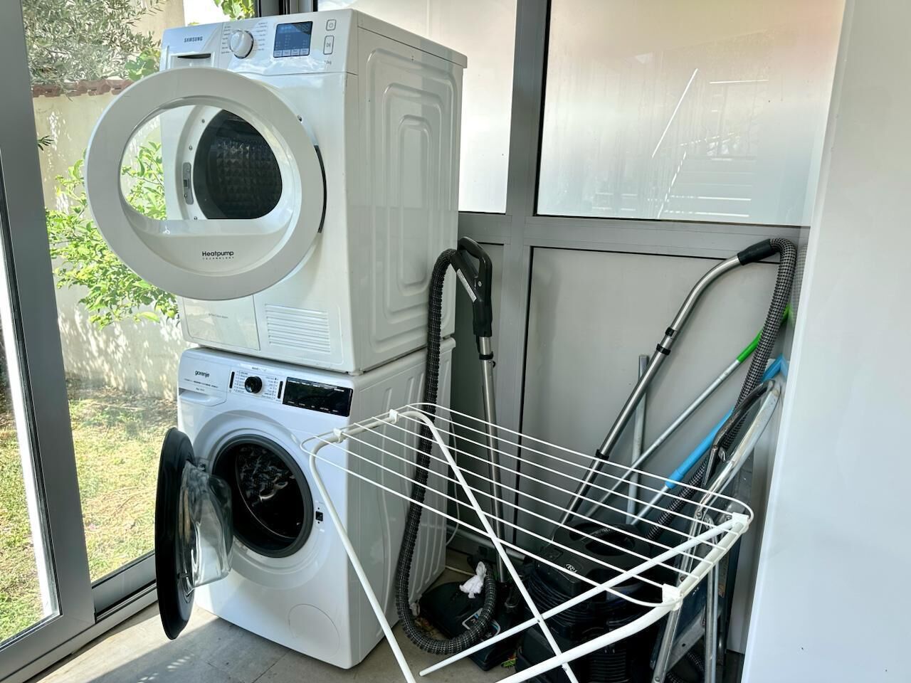 Un espacio pequeño para lavandería, con lavadora de carga frontal y un tendedero.