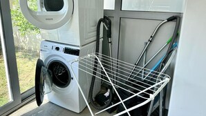 Un espacio pequeño para lavandería, con lavadora de carga frontal y un tendedero.