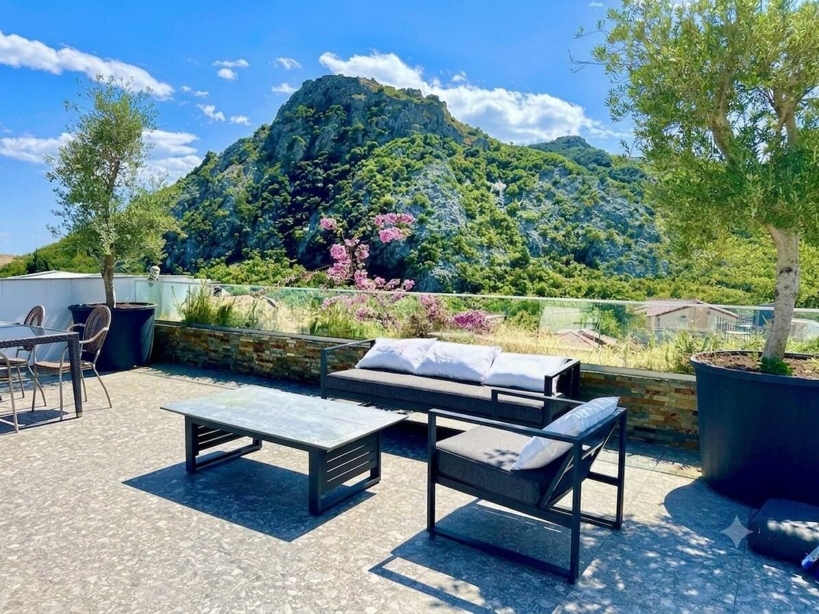 Un espacio exterior con asientos, un sofá, sillas, una mesa y vistas a la montaña.