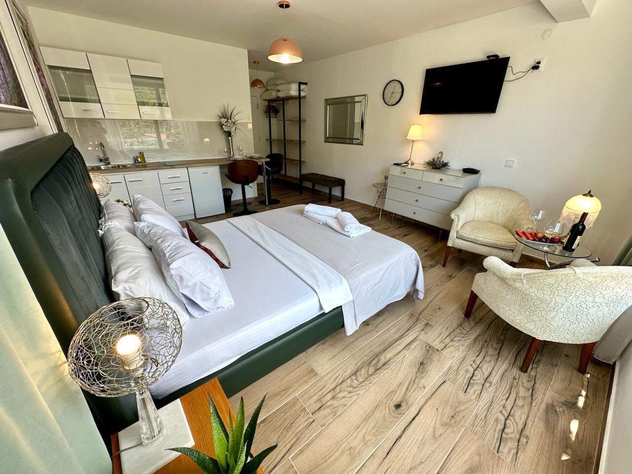 Una habitación de hotel con cama, escritorio, silla, televisor y un pequeño rincón de comedor.