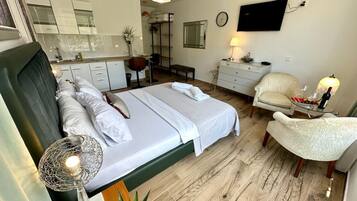 Una habitación de hotel con cama, escritorio, silla, televisor y un pequeño rincón de comedor.