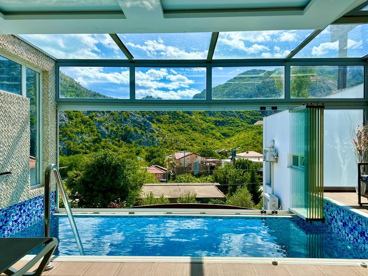 Ein Schwimmbecken mit Blick auf eine gebirgige Landschaft und Häuser.