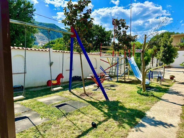 An outdoor playground with swings, a slide, and climbing structures.