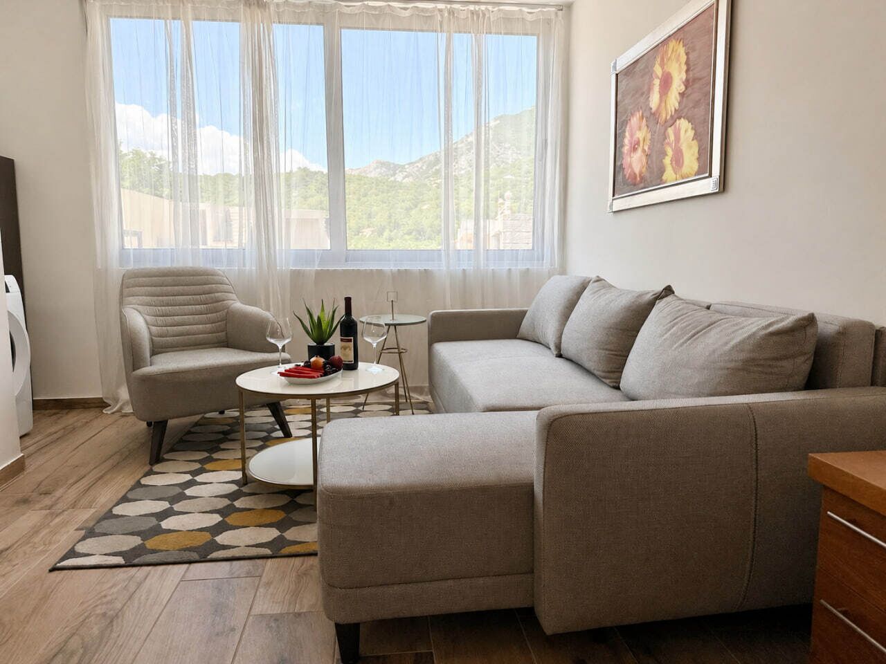 A living room with a sofa, a chair, a coffee table, and a painting on the wall.