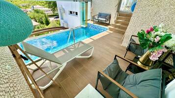 Un área de piscina interior moderna con balaustrada de vidrio, sillas de descanso y vistas al paisaje circundante.