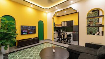 A modern living room with a television, a sofa, a coffee table, and a potted plant.