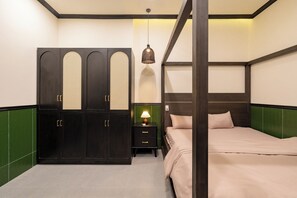A bedroom with a four-poster bed, a wardrobe with mirrored doors, a bedside lamp, and a green accent wall. - NHA TRONG NGO 2 (Da Nang)