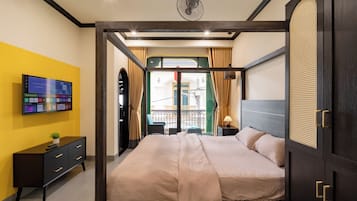 Habitación de hotel con cama, televisión, escritorio y vista a la calle por la ventana.