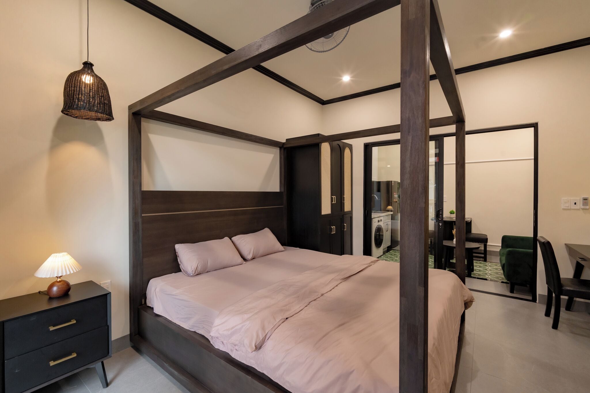 A modern bedroom with a four-poster bed, a bedside table with a lamp, and a wardrobe.