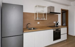 Een moderne keuken met een roestvrijstalen koelkast, een inbouwoven en een koffieapparaat.