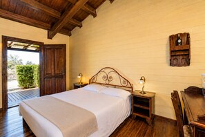 A bedroom with a wooden bed, two bedside tables with lamps, a wooden headboard, and a wooden shelf with a clock. - Wonderful private villa for 16 people with A/C, private pool, WIFI, TV, veranda and panoramic view (Santa Croce Camerina)