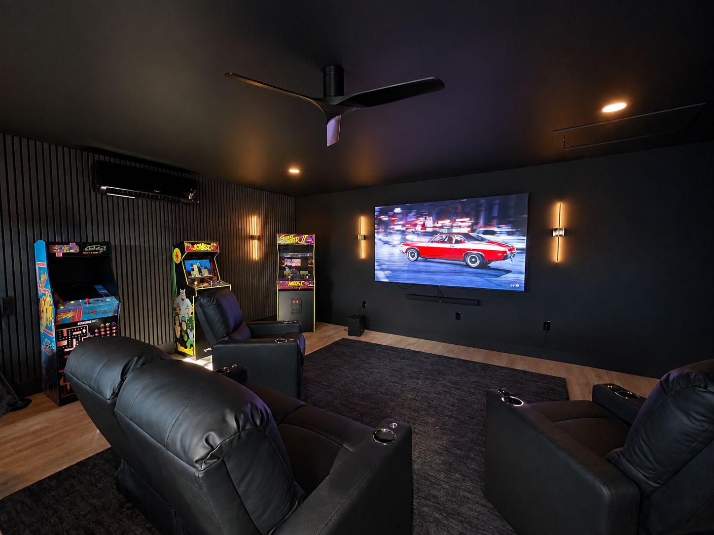 A home theater room with a large flat-screen TV, gaming consoles, and leather recliners.