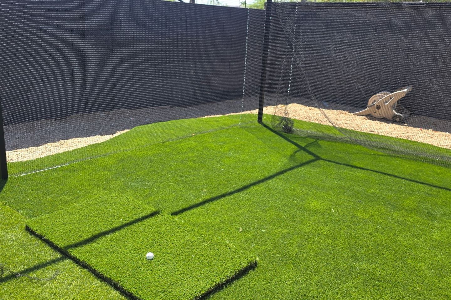 Et træningsområde til golf med et netindhegnet område, et putting green og en sandfælde.