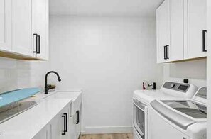 A compact kitchen with white cabinets, a sink, and a washing machine. - The Rally House-Premium 4 bed, priv pool, pickleball, 5 hole golf — mins to TPC (Scottsdale)