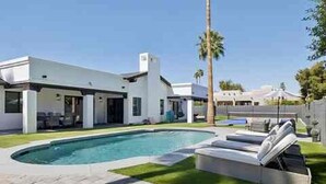 Une maison moderne dotée d’une piscine, d’un patio couvert et d’une pelouse bien entretenue.