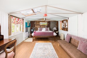 Une chambre à coucher avec un lit en bois, un canapé, un bureau et une fenêtre avec des rideaux.