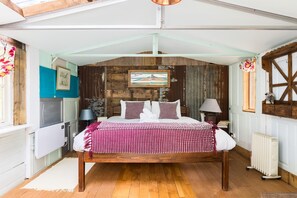 A bedroom with a wooden bed, a white radiator, and a rustic wall. - Stunning Glamping Retreat in the Woods - Pass the Keys (Moreton-in-Marsh)