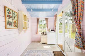 Un pasillo estrecho con piso de madera que conduce a una pequeña cocina con ventana y puerta.