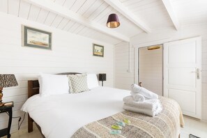 Un dormitorio con cama, dos lámparas de noche, una puerta y una lámpara en el techo.