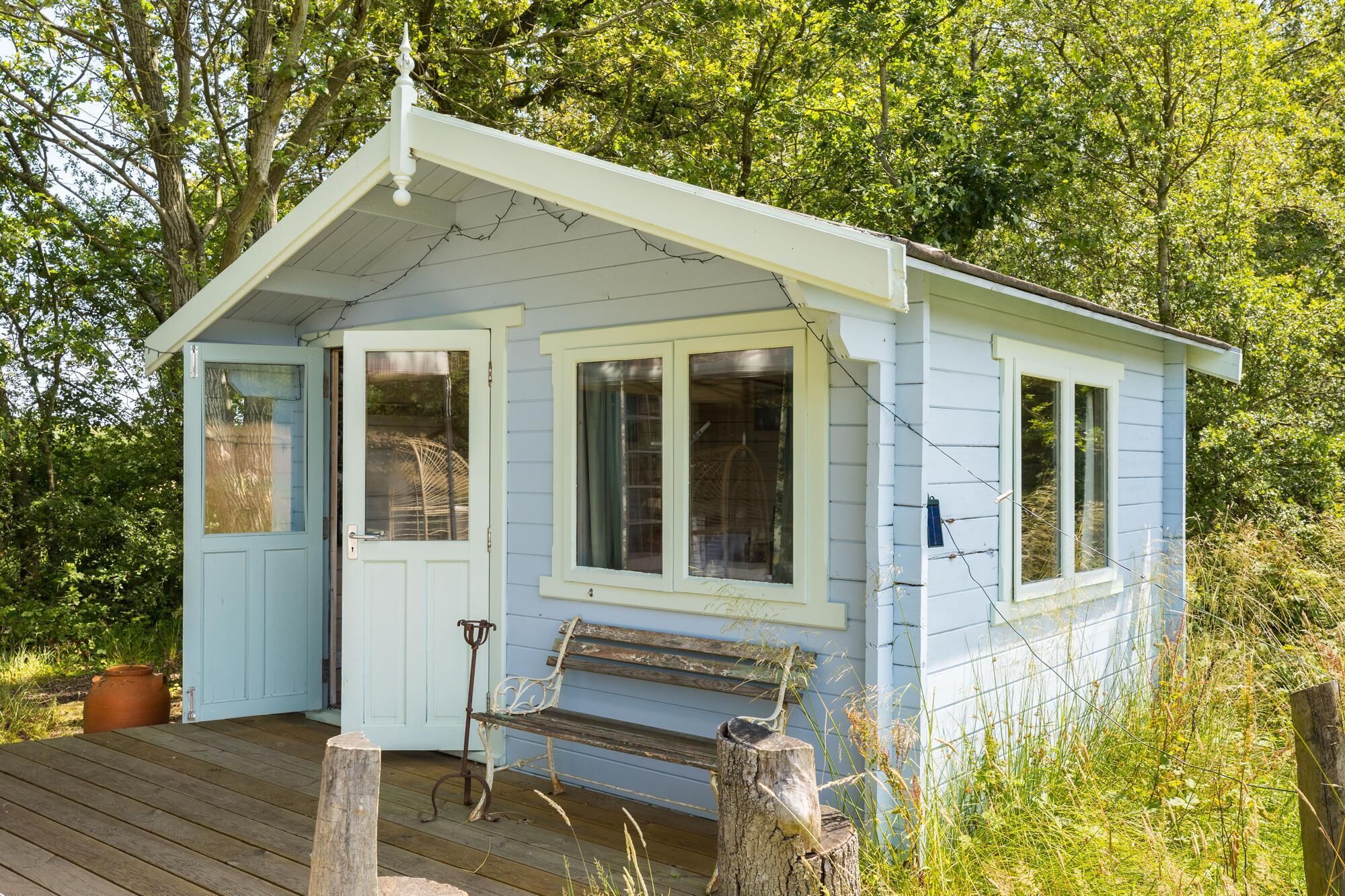 A small, single-story cabin with a porch, a bench, and a door.