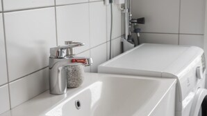 Une salle de bain moderne avec un lavabo blanc, un lave-linge et un miroir.