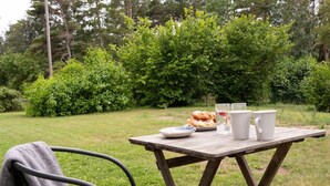 Un coin pique-nique aménagé avec une table, une chaise et une couverture, dans un espace extérieur herbeux.