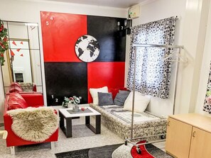 Ein modernes Wohnzimmer mit einem roten Sofa, einem kleinen Couchtisch, einem bettenartigen Sitzplatz und einer großen Wanduhr.