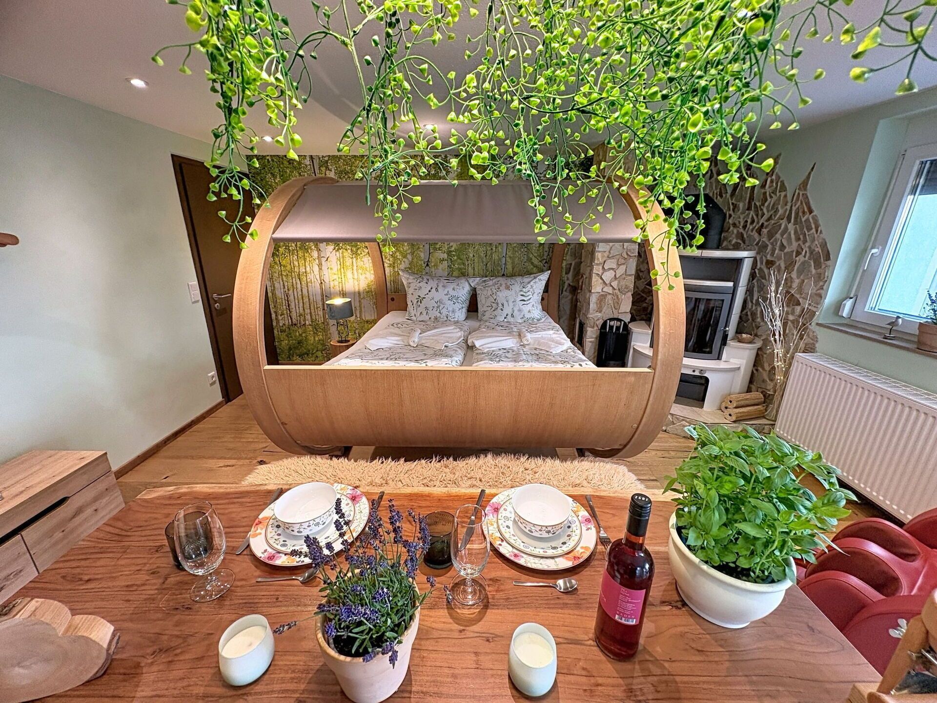A modern bedroom with a curved bed, a dining table set with dinnerware, and a potted plant.
