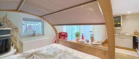 Una habitación funcional con cama, kitchenette pequeña y ventana.