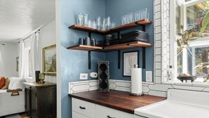 A kitchen with wooden shelves, white cabinets, and a window with a view. - Lovely downtown Chico home (Chico)