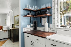 A kitchen with wooden shelves, white cabinets, and a window with a view. - Lovely downtown Chico home (Chico)