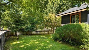 A residential property with a fenced backyard, a wooden deck, and a house with a dark exterior and large windows. - Lovely downtown Chico home (Chico)