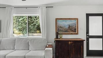 A living room with a sofa, a painting, a cabinet, and a door.