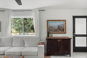 Ein Wohnzimmer mit einer Couch, einem Gemälde, einer Kommode und einer Tür.