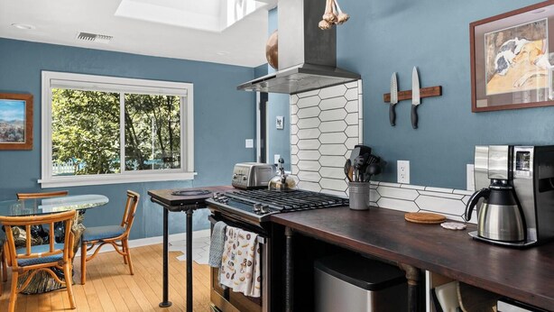 A modern kitchen with a gas stove, a coffee maker, and a window with a view of trees. - Lovely downtown Chico home (Chico)