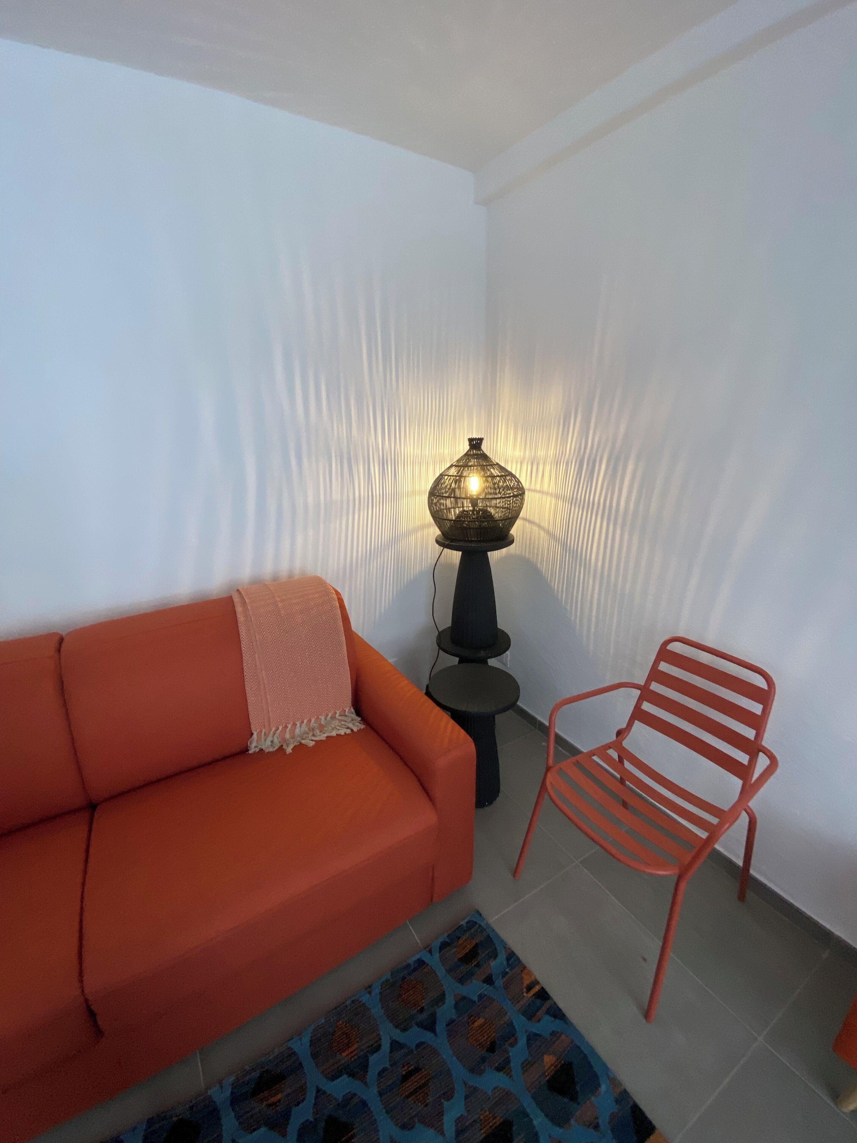 A room with a sofa, a chair, a lamp, and a patterned rug.
