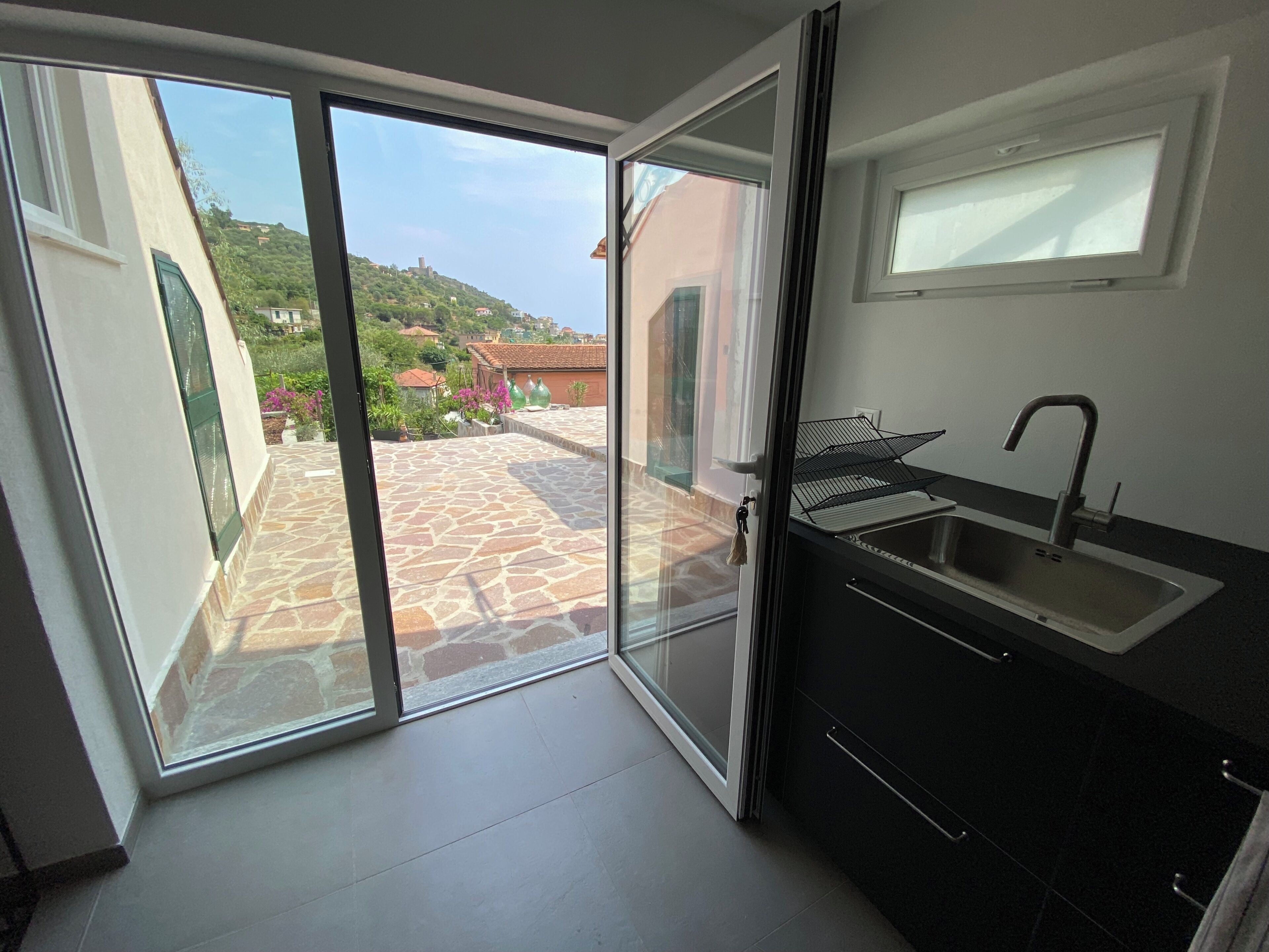 Eine moderne Küche mit integriertem Spülbecken und einer Schiebeglastür, die auf eine Terrasse im Freien führt.