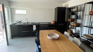 Una cocina moderna con una mesa de comedor de madera, armarios negros y una estantería empotrada.
