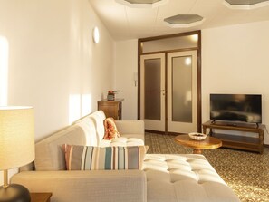 Habitación de hotel con sofá, televisión, una mesita y alfombra estampada.