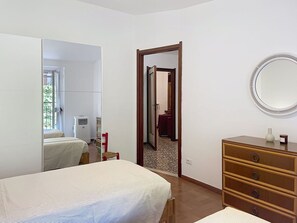 Ein Schlafzimmer mit einem Bett, einem Schminktisch, einem Spiegel und einer Tür zu einem weiteren Raum.