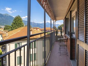 Ein Balkon mit Blick auf Berge, einem Tisch mit Stühlen und einem Blumentopf.