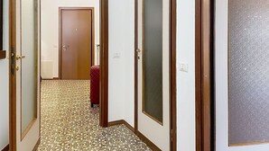 En hall med ett mönstrat golv, trädörrar och en resväska.