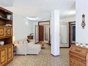 Een kamer met een bank, een houten kast, een spiegel en een vloer met een patroon.