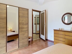 Ein Schlafzimmer mit einem Bett, einem Schminktisch, einem Spiegel und einem Kleiderschrank.
