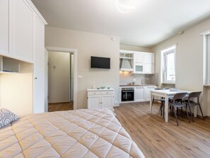 Ein kleines Zimmer mit Bett, Küchenzeile und Essecke.