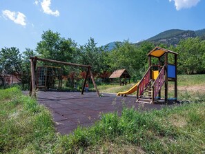 Ein Spielplatz mit Rutsche, Klettergerüsten und einer kleinen Schutzhütte.