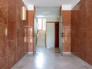 Ein Korridor mit Marmorwänden und einer Treppe, die zu einer Tür führt.