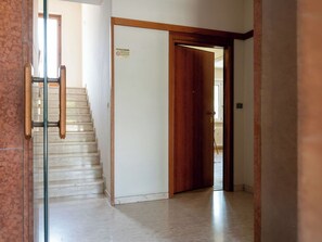 Ein Flur mit einer Holztür, einer Treppe und einer Glastür.